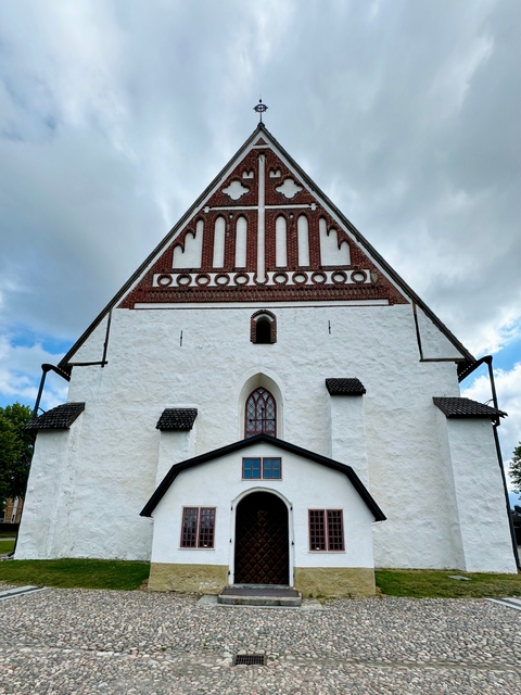      A white and red brick church under cloudy skies.
  