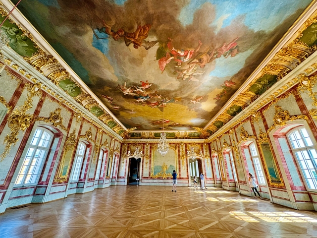 Ornate interior room with people observing the ceiling artwork.