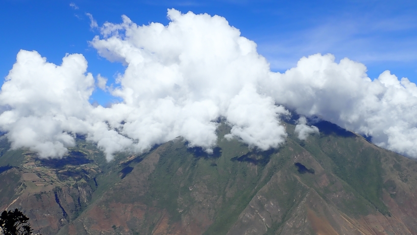 Mountain landscape under clouds with bright blue sky.