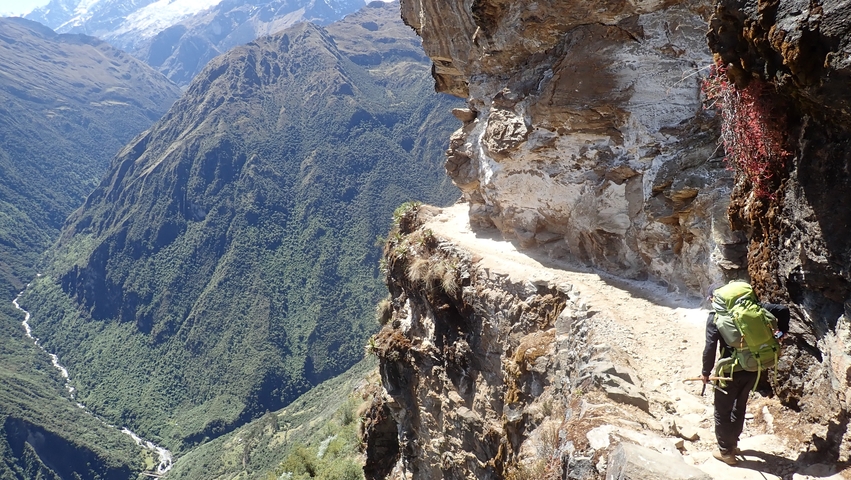 Hiker walking along a narrow mountain trail.