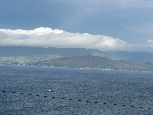Mountainous coastal landscape with cloudy sky.