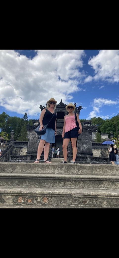       Two women standing in front of an ancient architectural site.
  
