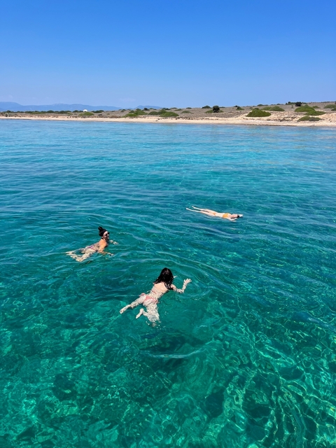 Three people swimming in clear blue water.