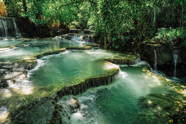 Series of terraced waterfalls in a lush forest setting.
