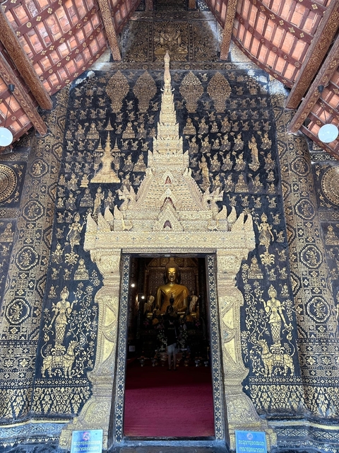      Decorative temple facade with gold details and a Buddha statue.
  