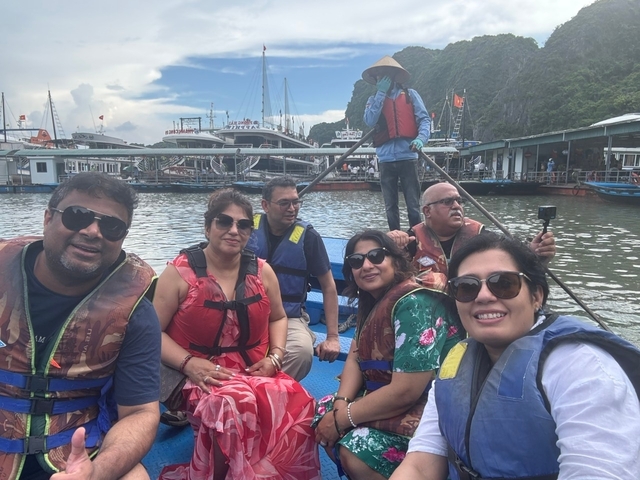 Group of people wearing life jackets on a boat with dock in the background.