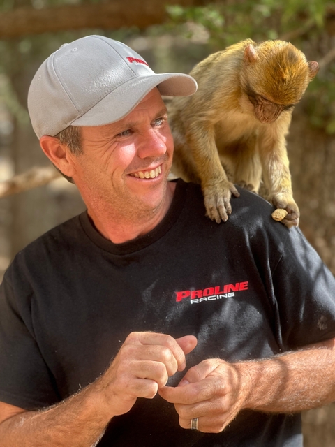       Smiling man with a monkey on his shoulder.
  