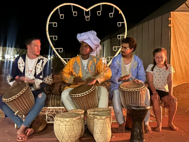       Musicians playing drums in a nighttime setting.
  
