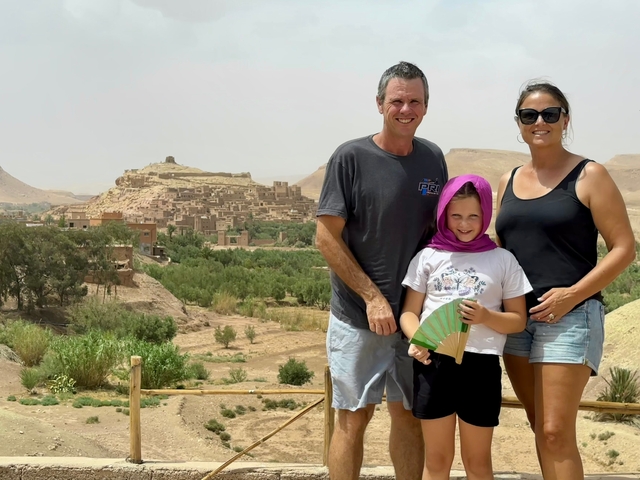       Family posing in front of a traditional Moroccan village.
  