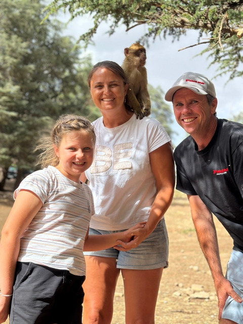       Family smiling with a monkey perched on one person.
  