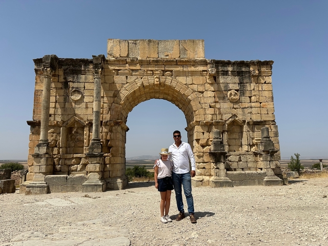       People posing in front of a large stone archway.
  
