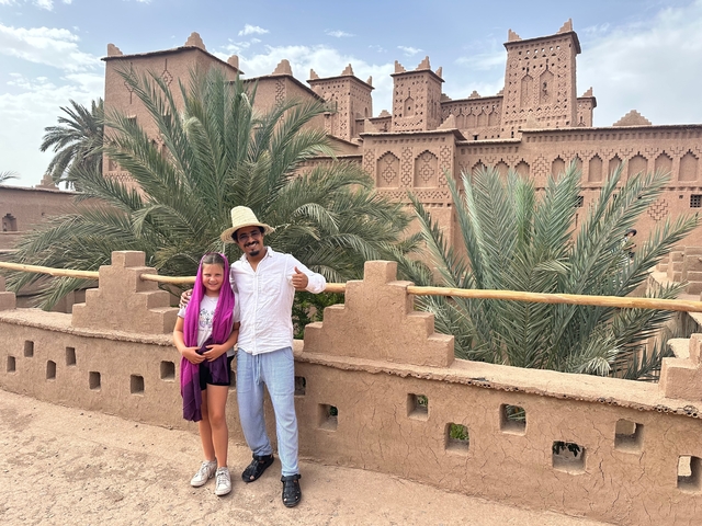       People posing with a traditional Moroccan building in the background.
  