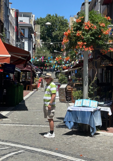 Man standing in a colorful, decorated alleyway.