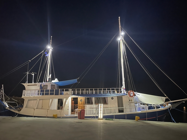       Boat docked at night with lights on.
  