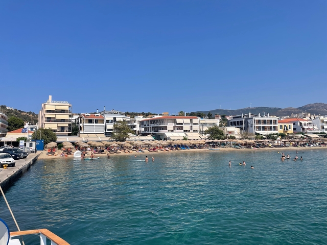       Beachfront with people swimming and sunbathing.
  