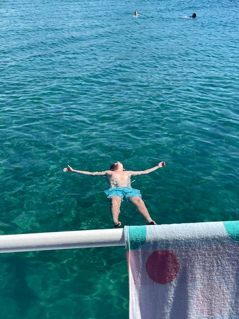       Person floating on their back in clear water.
  