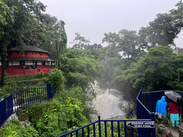 People standing near a waterfall with lush green surroundings.