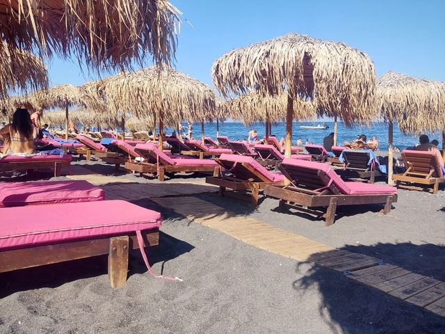       Beach with sunbeds and straw parasols by the sea.
  