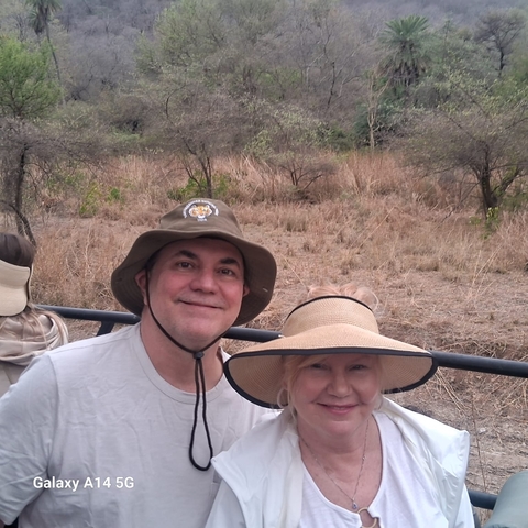 Two people on a safari with dry terrain in the background.