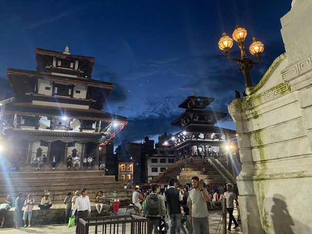 People gathered at a lit-up temple in the evening.