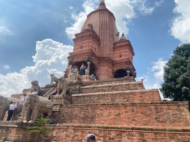 A large temple structure with visitors climbing its steps.