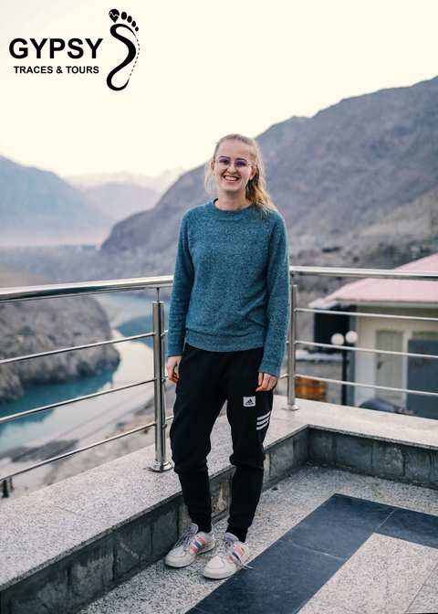       Person standing on a balcony with mountains in the background.
  