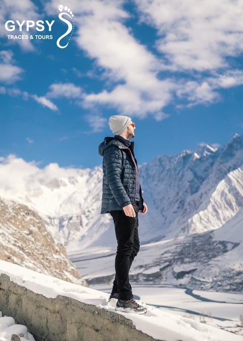       Person in winter clothing looking at snow-capped mountains.
  