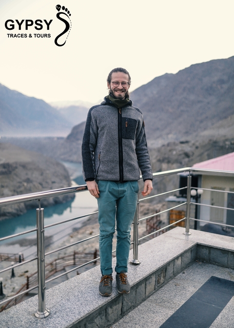       Person standing on a balcony with a mountainous landscape in the back.
  