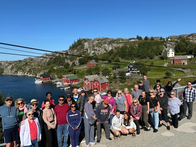       Group of people posing by a scenic coastline with colorful houses.
  