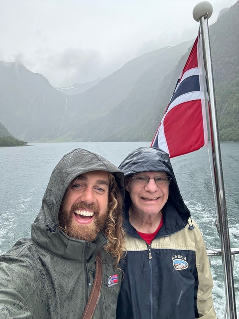       Two people smiling with a flag on a boat.
  