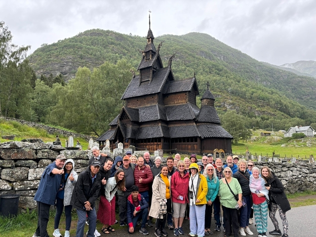       People posing in front of a traditional wooden church.
  