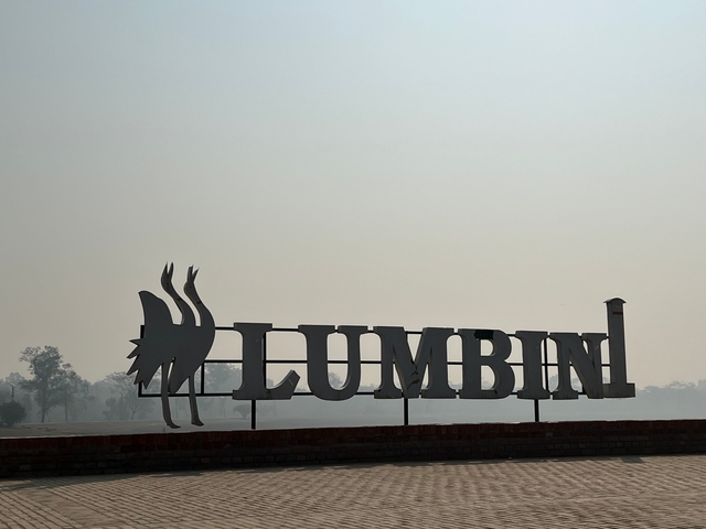       Silhouette of a Lumbini sign against a hazy sky.
  