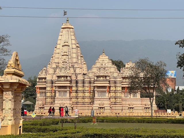       A large, intricately carved temple with people walking in front.
  