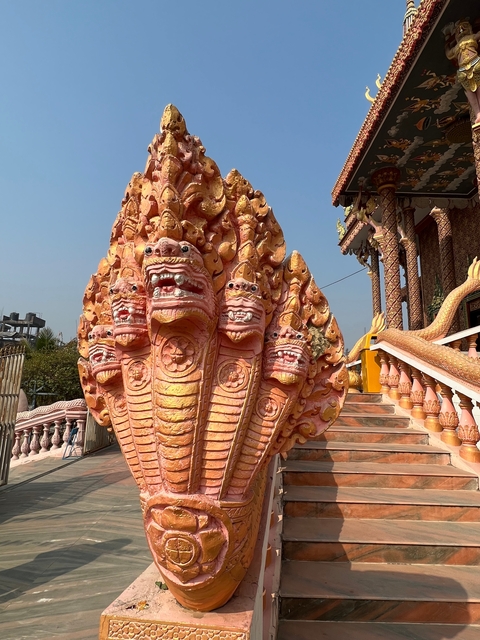       A statue of a multi-headed serpent with temple architecture in the background.
  