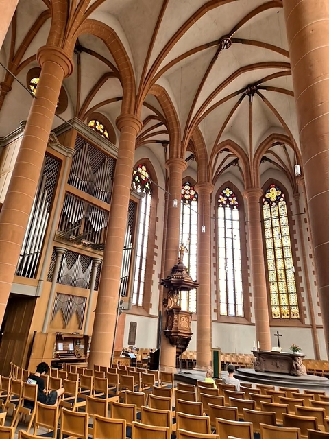 Interior of a church with stained glass windows and organ pipes.