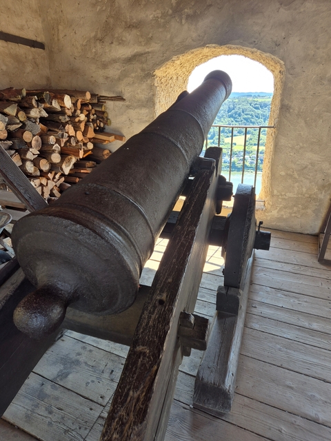 Ancient cannon displayed indoors with wooden flooring.