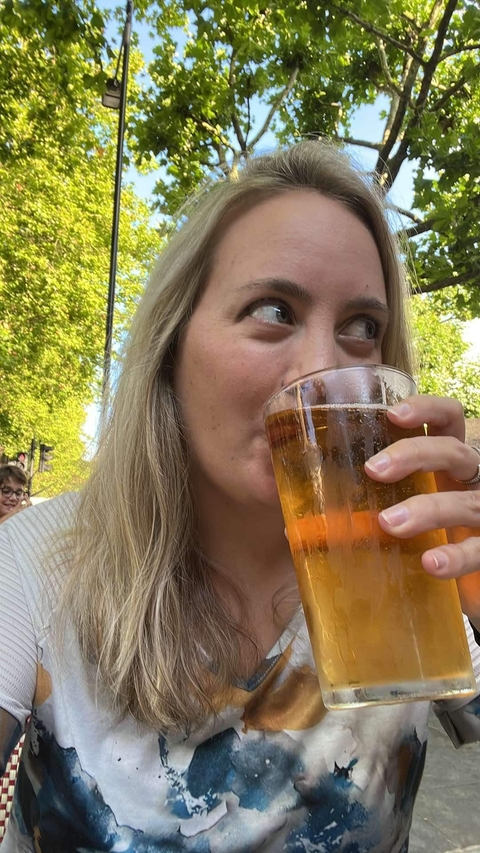 Woman drinking from a glass in an outdoor setting.
