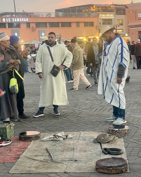       People in traditional clothing standing on a tiled street.
  