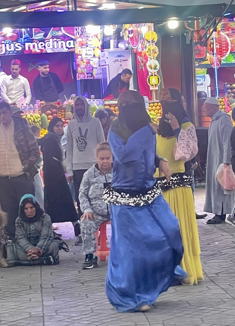       People gathered at a market with stalls and performers.
  