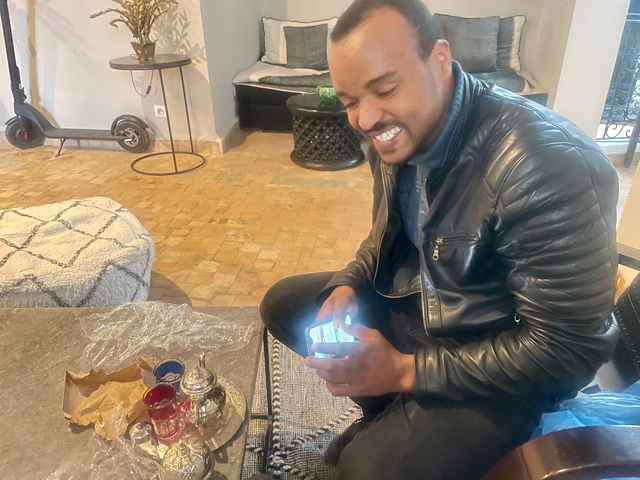       Person smiling while seated on the floor with a tray and tea set.
  