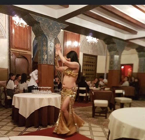       Belly dancer performing in a room with an audience.
  