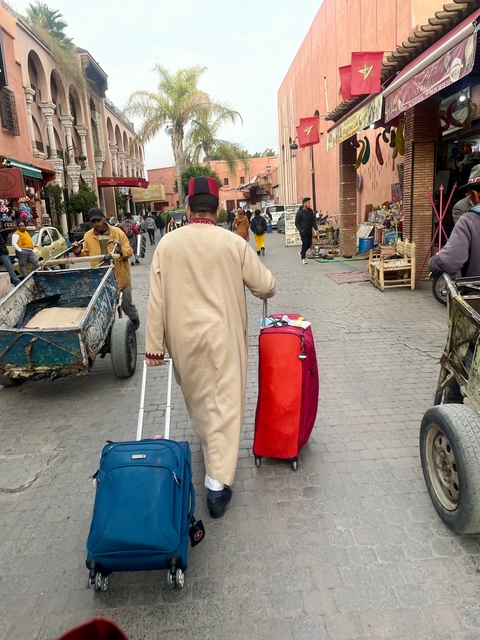       Street scene in a Moroccan city with people and carts.
  