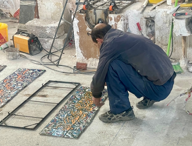       Man working on decorative tiles.
  