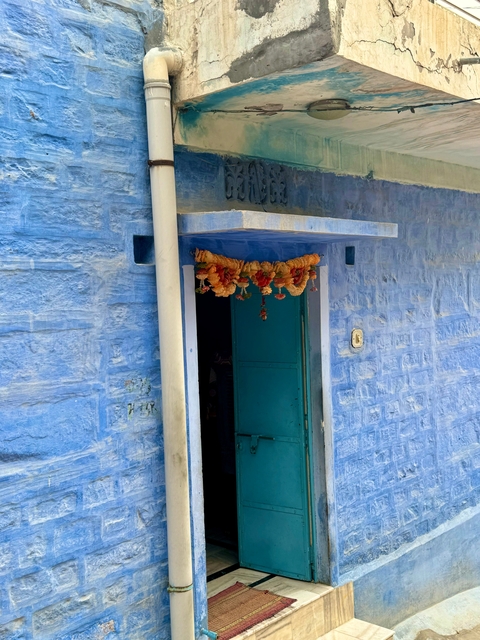       Vibrantly painted blue and green door with decorative garland.
  