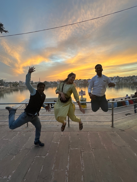       Three people joyfully jumping in front of a scenic sunset background.
  