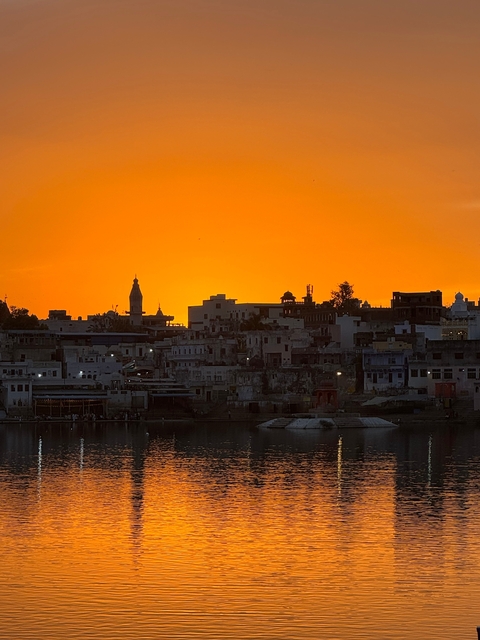       City skyline silhouette against a vibrant orange sunset.
  