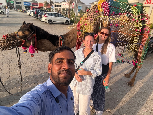       Selfie with friends in front of a decorated camel.
  