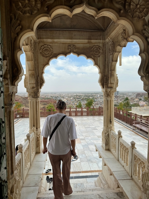       Person with cityscape view from ornate balcony.
  