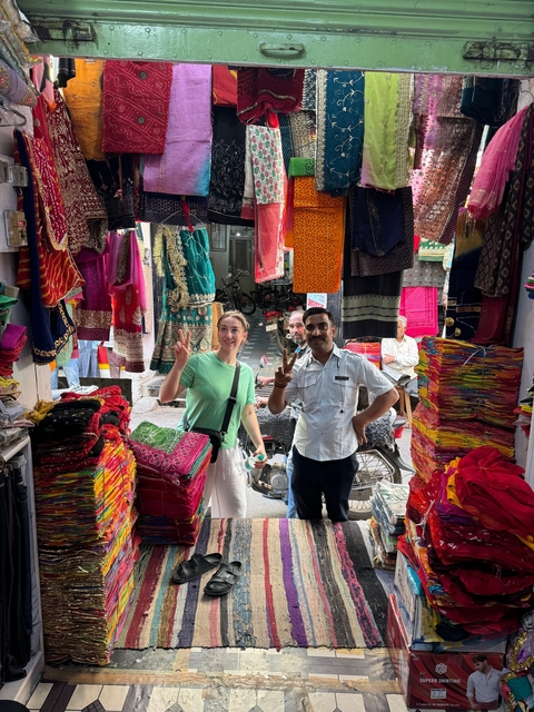       Street market with colorful fabrics and two people posing
  