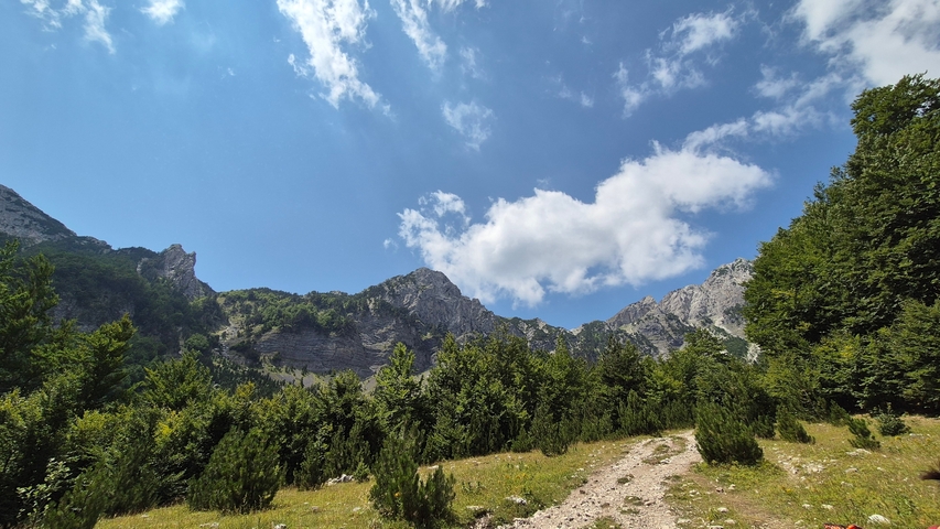 Green valleys with rocky mountain backdrop.